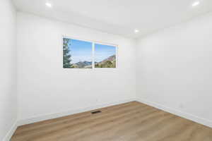 Empty room with a mountain view, light wood-type flooring, and recessed lighting