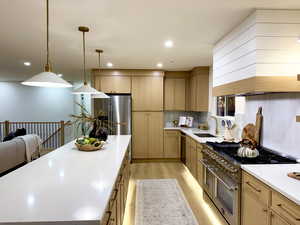 Kitchen with stainless steel appliances, light wood finished floors, light stone counters, pendant lighting, and recessed lighting