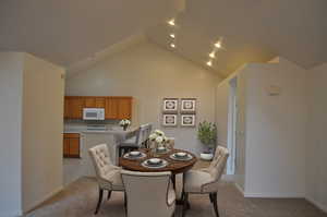Dining room with light carpet and high vaulted ceiling