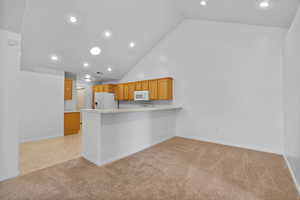 Kitchen featuring high vaulted ceiling, light colored carpet, recessed lighting, light countertops, and a peninsula