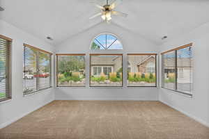 Unfurnished sunroom featuring vaulted ceiling and carpet
