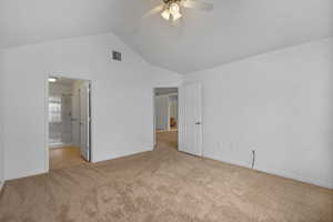 Unfurnished bedroom featuring light colored carpet, ceiling fan, connected bathroom, and high vaulted ceiling