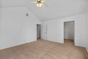 Unfurnished bedroom featuring high vaulted ceiling, a spacious closet, light carpet, and a ceiling fan