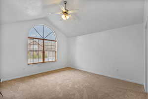 Additional living space with lofted ceiling, light carpet, and ceiling fan