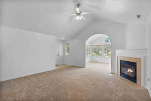 Unfurnished living room with light carpet, a fireplace, ceiling fan, and high vaulted ceiling
