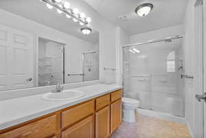 Bathroom with a shower stall, vanity, light tile patterned floors, and a walk in closet