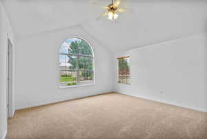 Unfurnished room with lofted ceiling, light carpet, and ceiling fan