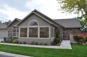 View of front of home featuring stone siding, a front yard, stucco siding, and an attached garage