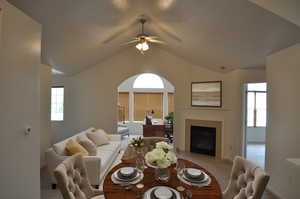 Carpeted living room featuring ceiling fan, a fireplace, and lofted ceiling