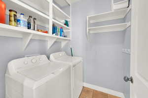 Laundry area with light tile patterned floors and independent washer and dryer