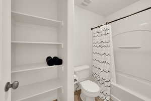 Bathroom featuring shower / bath combination with curtain and toilet