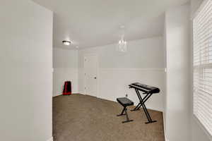 Exercise room with carpet flooring and a chandelier
