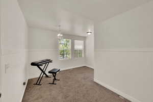 Spare room with a wainscoted wall, carpet floors, and a chandelier