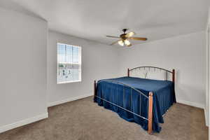 Carpeted bedroom featuring ceiling fan and a textured ceiling