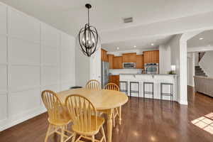 Dining area with dark wood-type flooring, a chandelier, recessed lighting, and stairway