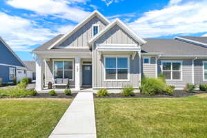 View of front of home featuring board and batten siding, roof with shingles, a porch, and a front yard