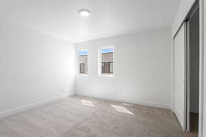 Unfurnished bedroom featuring light carpet and a closet