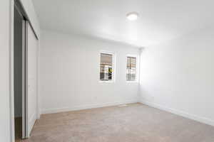 Unfurnished bedroom with light colored carpet and a closet
