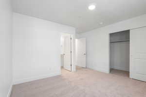 Unfurnished bedroom featuring light carpet, a closet, and connected bathroom