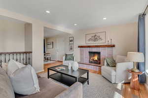Living room featuring wood finished floors, recessed lighting, and a brick fireplace