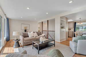 Living area featuring light wood finished floors, recessed lighting, a chandelier, and built in features
