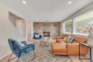 Carpeted living area featuring a stone fireplace and recessed lighting