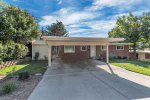 Ranch-style home featuring a front lawn, concrete driveway, and a porch