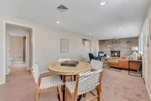 Dining room with a stone fireplace, light carpet, and recessed lighting