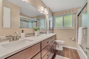 Bathroom with shower / bath combination with glass door, double vanity, wood finish floors, and decorative backsplash