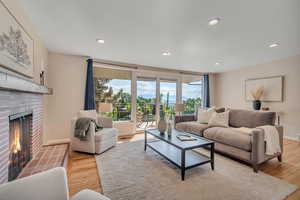 Living room featuring recessed lighting, light wood finished floors, and a brick fireplace