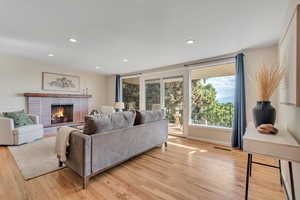 Living area featuring light wood-type flooring, recessed lighting, and a fireplace