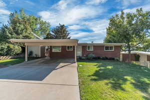 Ranch-style house with a front yard, concrete driveway, and brick siding