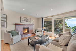 Living room featuring wood finished floors, recessed lighting, and a brick fireplace