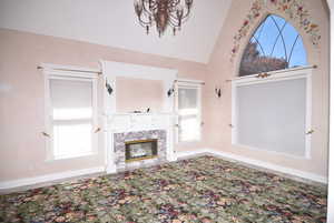 Unfurnished living room featuring a premium fireplace and vaulted ceiling