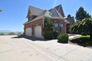 View of home's exterior featuring brick siding, a garage, roof with shingles, driveway, and a mountain view