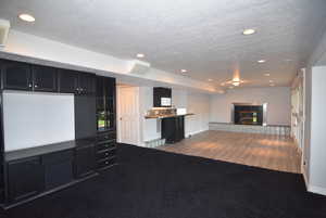 Unfurnished living room featuring dark carpet, a textured ceiling, recessed lighting, and a fireplace