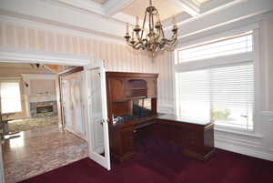 Office featuring plenty of natural light, a chandelier, a glass covered fireplace, beamed ceiling, and wallpapered walls
