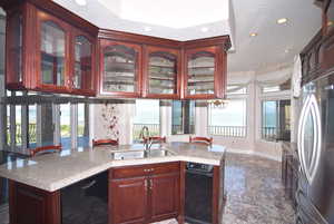 Kitchen featuring freestanding refrigerator, glass insert cabinets, recessed lighting, plenty of natural light, and a textured ceiling