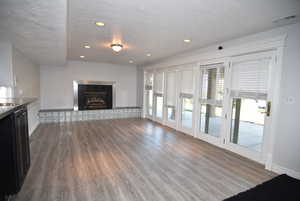 Unfurnished living room featuring a textured ceiling, dark wood-style floors, a tiled fireplace, and recessed lighting