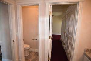 Bathroom with toilet and dark tile patterned flooring