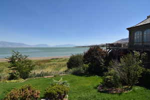 View of grassy yard featuring a deck with water view