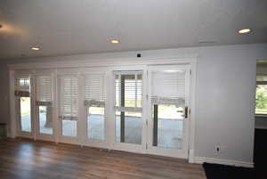 Doorway to outside featuring a textured ceiling, wood finished floors, and recessed lighting