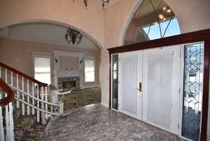 Foyer entrance featuring a towering ceiling, a premium fireplace, french doors, and arched walkways