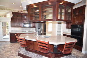Kitchen featuring a breakfast bar area, plenty of natural light, black appliances, backsplash, and recessed lighting