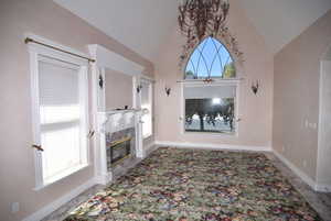 Unfurnished living room with a high end fireplace and high vaulted ceiling