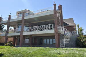 Rear view of house with a balcony, a chimney, stairway, a patio area, and brick siding