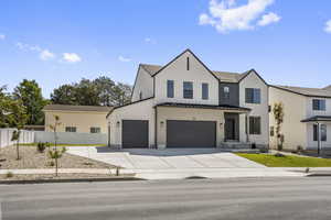 Modern inspired farmhouse featuring a standing seam roof, a metal roof, driveway, an attached garage, and stucco siding