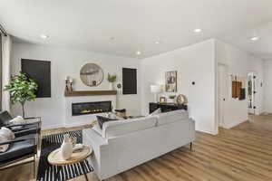 Living area with recessed lighting, light wood-style flooring, and a glass covered fireplace