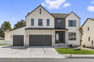 Modern farmhouse style home with a standing seam roof, a metal roof, concrete driveway, an attached garage, and stucco siding