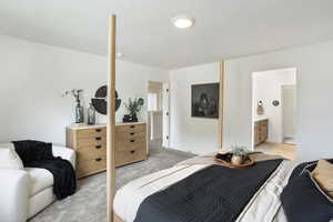 Bedroom featuring light colored carpet, a textured ceiling, and connected bathroom